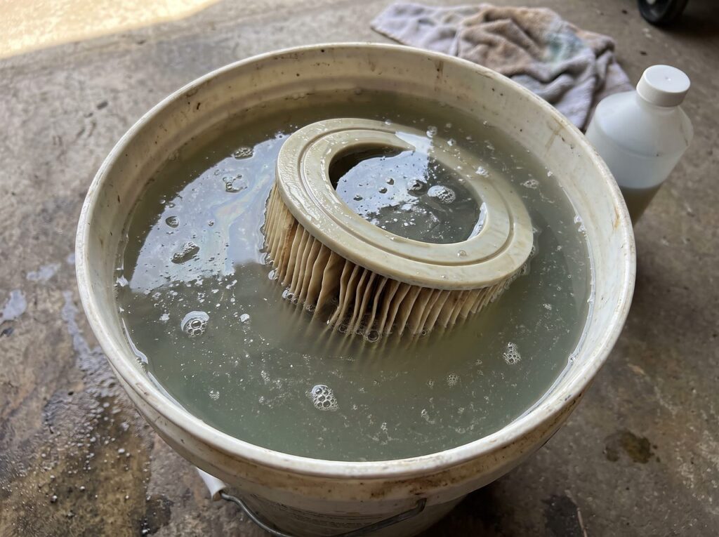 pleated spa filter cartridge fully submerged in a bucket of cleaning solution