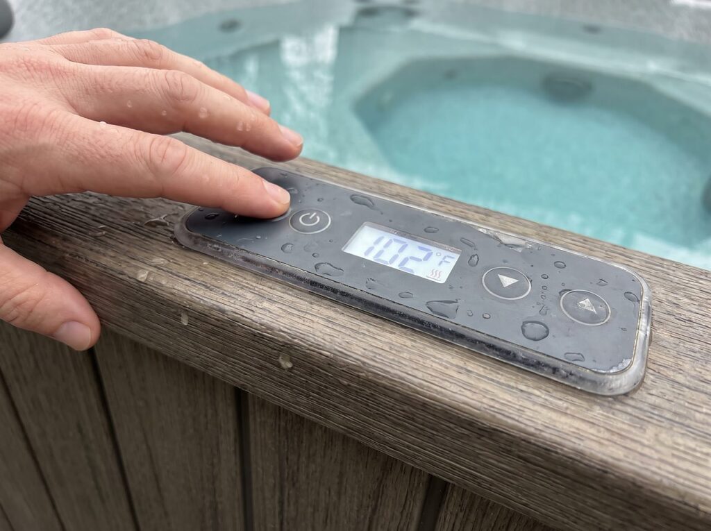 a hand checking a spa control panel's heater and temperature setting