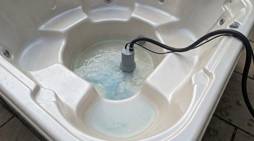 a submersible utility pump draining the last water from a hot tub footwell