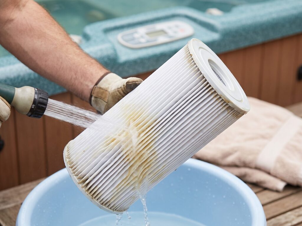 rinsing a pleated spa filter cartridge with a hose before refilling the tub