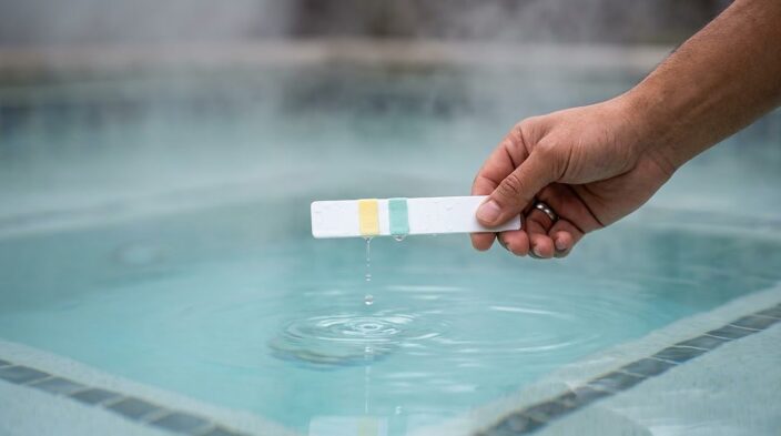 a wet test strip with two distinct chlorine reading pads held above spa water