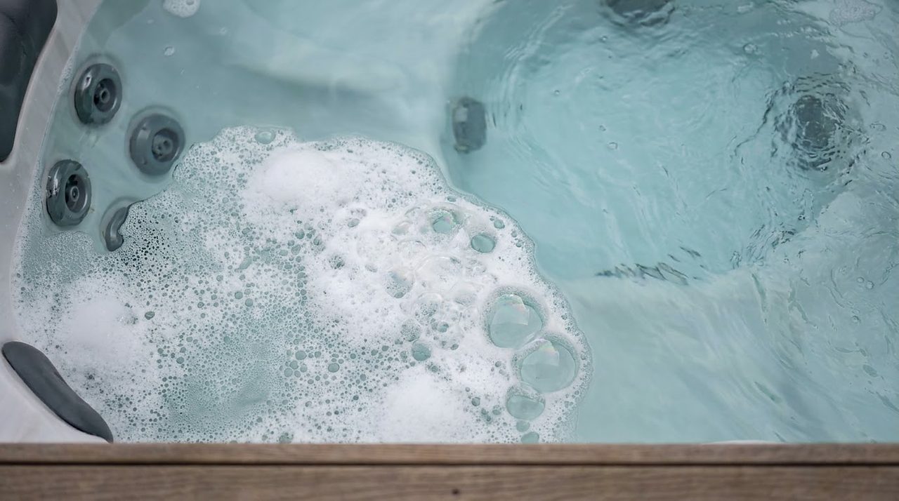 closeup of greasy white foam bubbles floating on hot tub water surface