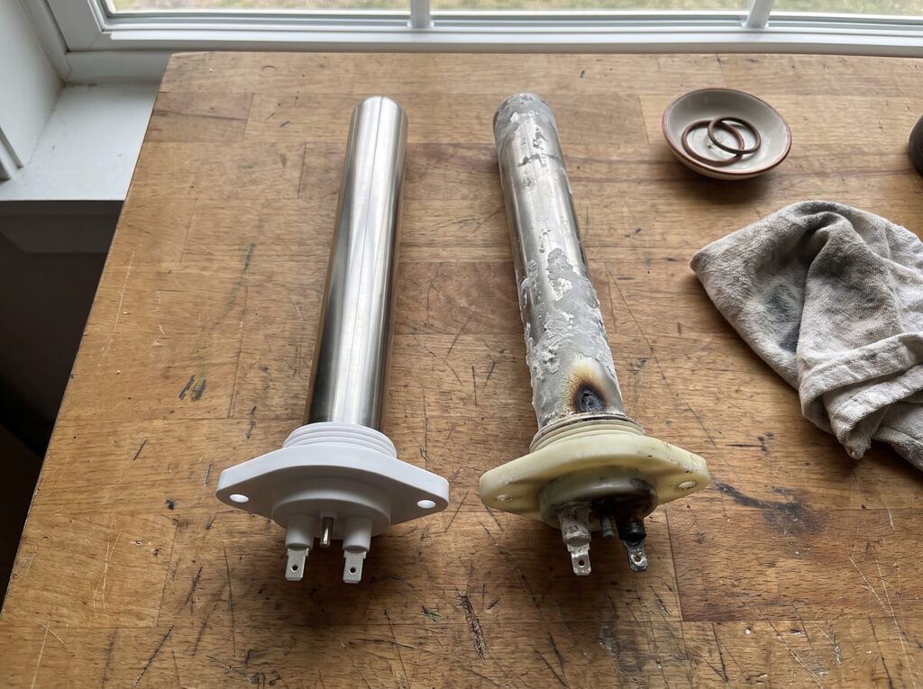 a new heater element beside a scaled, worn one on a workbench