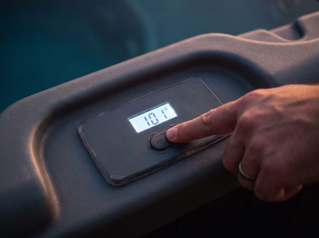finger pressing a reset button on a spa control panel showing a temperature readout