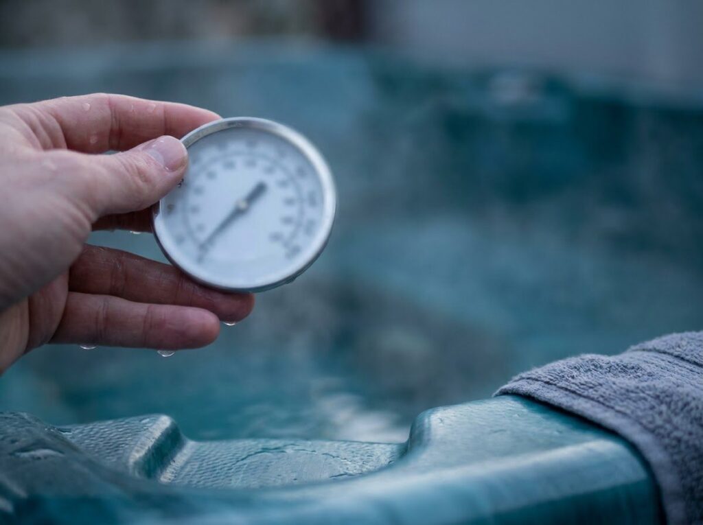hand holding a floating thermometer above steaming hot tub water to check temperature